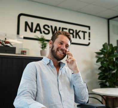 Medewerker glimlachend aan de telefoon met een kandidaat